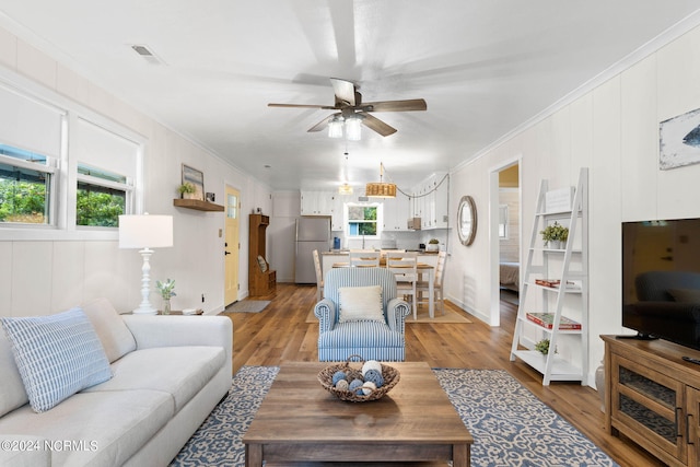 living room featuring ceiling fan, light wood-type flooring, and ornamental molding