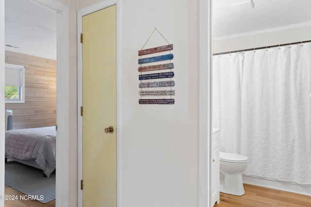 bathroom with curtained shower, hardwood / wood-style floors, wooden walls, and toilet