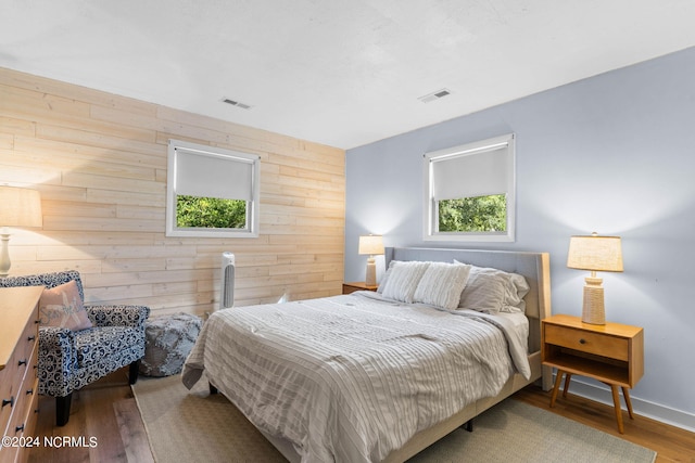 bedroom with wood-type flooring and wood walls