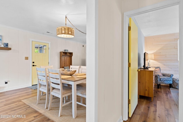 dining area featuring wooden walls, hardwood / wood-style flooring, and crown molding