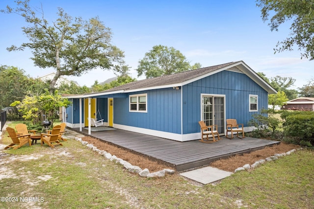 back of house featuring a fire pit, a deck, and a yard