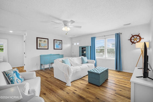 living room with hardwood / wood-style flooring, plenty of natural light, ceiling fan, and a textured ceiling