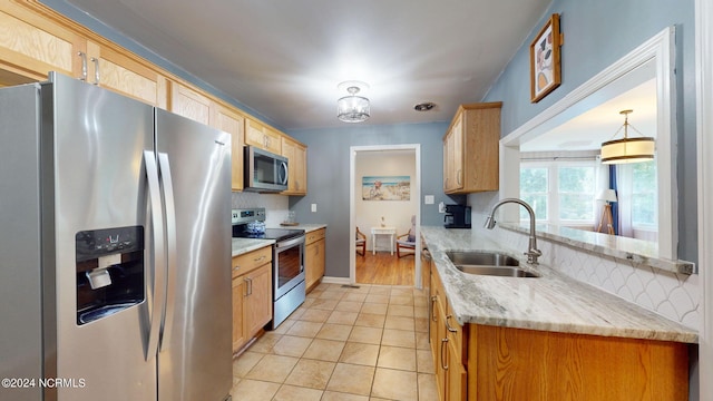 kitchen featuring tasteful backsplash, sink, appliances with stainless steel finishes, decorative light fixtures, and light stone countertops