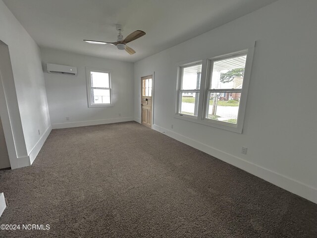 spare room with plenty of natural light, ceiling fan, a wall unit AC, and carpet flooring