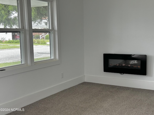 unfurnished living room with a glass covered fireplace and carpet