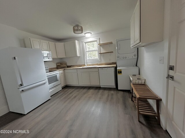 kitchen featuring light wood-type flooring, stacked washer and dryer, white appliances, white cabinetry, and sink