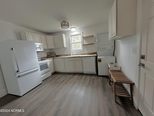 kitchen with white appliances, a sink, light countertops, light wood-style floors, and stacked washer and clothes dryer