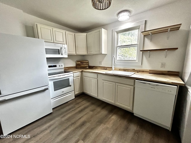 kitchen with a sink, white appliances, dark wood finished floors, and butcher block counters