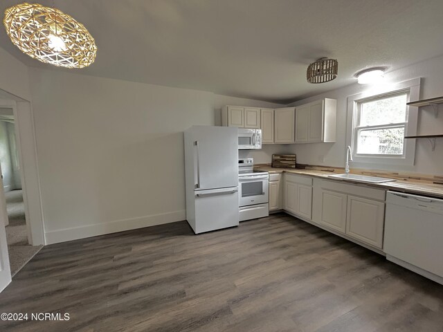 kitchen with decorative light fixtures, white appliances, white cabinetry, sink, and wood-type flooring