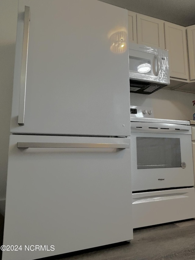 104 Charles St, Hertford, NC 27944 - kitchen with white appliances, wood finished floors, and white cabinetry