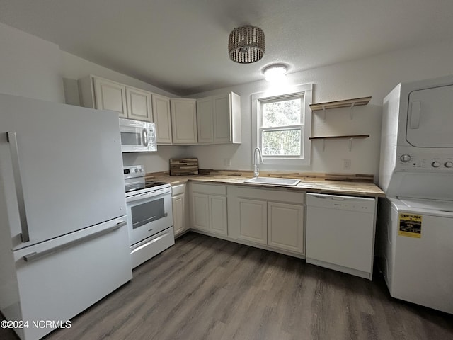 kitchen with white appliances, wood finished floors, a sink, light countertops, and stacked washer and dryer