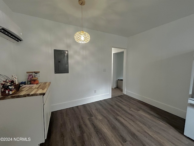 unfurnished dining area featuring dark wood finished floors, electric panel, baseboards, and a wall unit AC