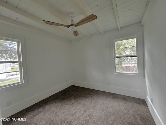 empty room with baseboards, beamed ceiling, wood ceiling, a ceiling fan, and dark colored carpet