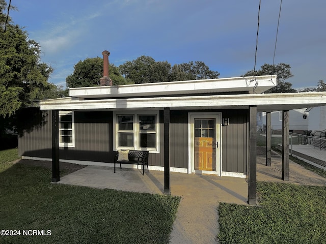 back of house featuring a yard, a patio area, and board and batten siding