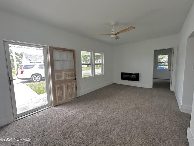 unfurnished living room featuring ceiling fan and carpet floors