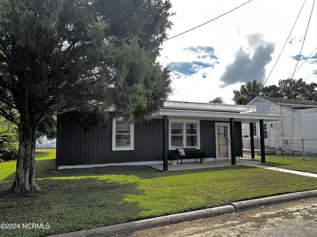 view of front of house featuring board and batten siding, a front lawn, and fence