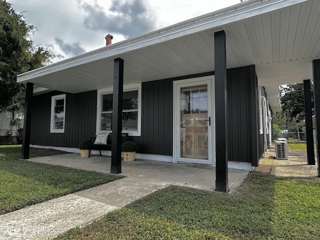 property entrance featuring a porch, a yard, and board and batten siding