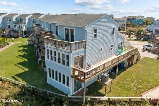 rear view of house with central AC, a yard, and a balcony