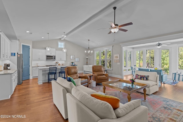 living room featuring ceiling fan with notable chandelier, light wood-type flooring, and vaulted ceiling with beams