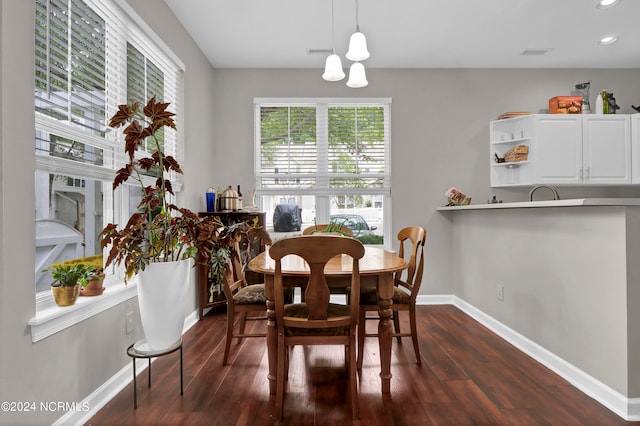 dining room with an inviting chandelier, a healthy amount of sunlight, and dark hardwood / wood-style floors