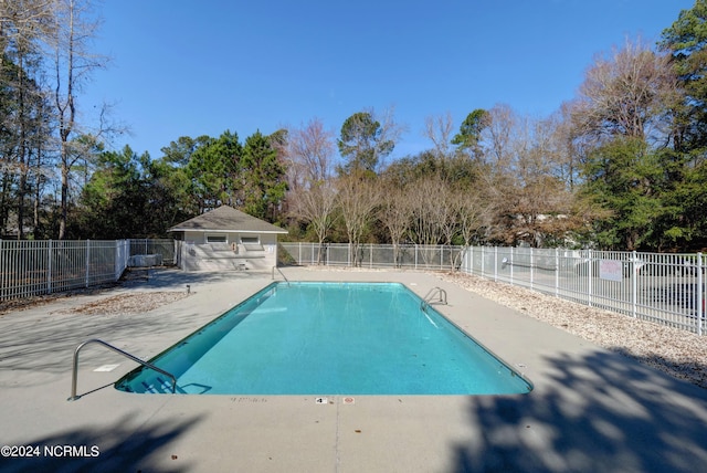 view of swimming pool featuring a patio and an outbuilding