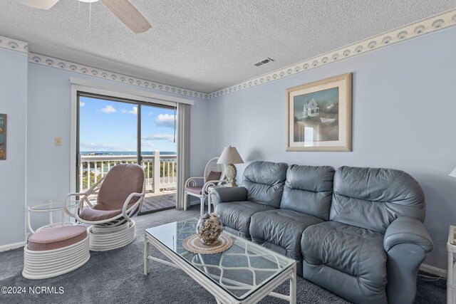 carpeted living room featuring ceiling fan and a textured ceiling