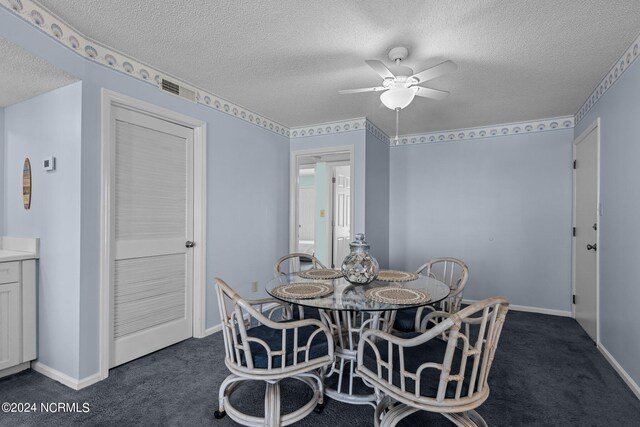 dining space featuring dark colored carpet, a textured ceiling, and ceiling fan