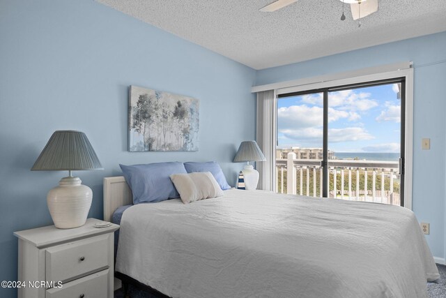 bedroom with a textured ceiling, a water view, access to outside, and ceiling fan