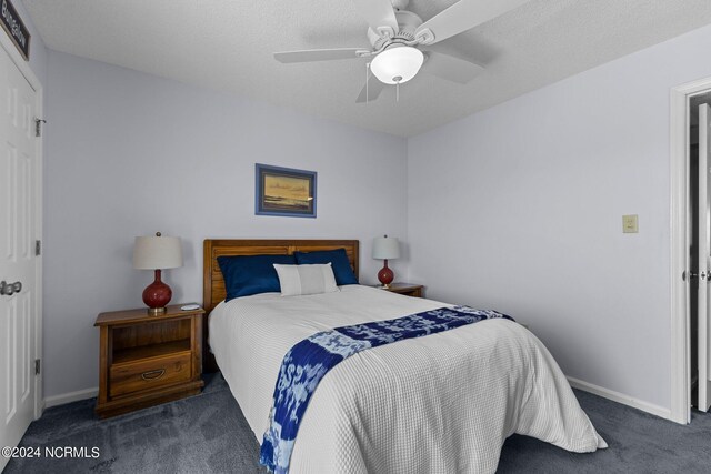 bedroom featuring ceiling fan, a textured ceiling, and dark carpet