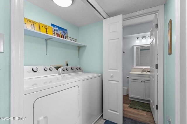 laundry room featuring sink, a textured ceiling, washing machine and dryer, and dark hardwood / wood-style flooring