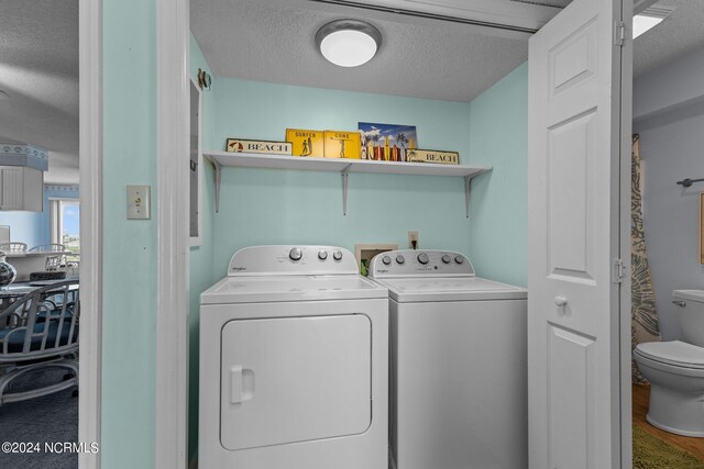 clothes washing area featuring washing machine and dryer, a textured ceiling, and hardwood / wood-style floors