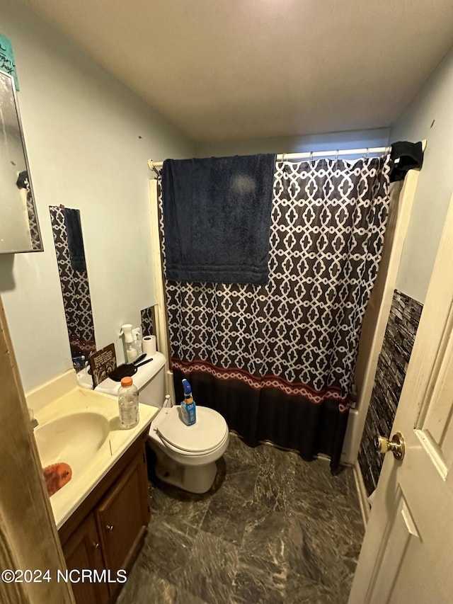 bathroom featuring toilet, marble finish floor, and vanity