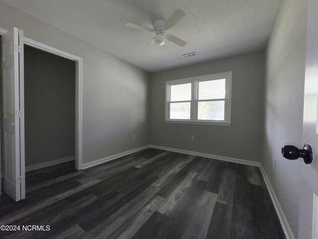 unfurnished room with ceiling fan, dark hardwood / wood-style floors, and a textured ceiling