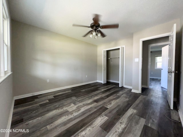 unfurnished bedroom with a textured ceiling, dark hardwood / wood-style flooring, ceiling fan, and a closet