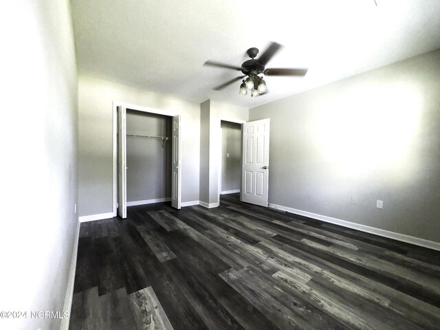 unfurnished bedroom with ceiling fan, a closet, and dark hardwood / wood-style flooring