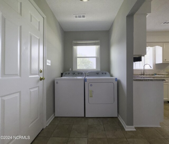 laundry room with tile patterned flooring, a textured ceiling, washer and dryer, and sink