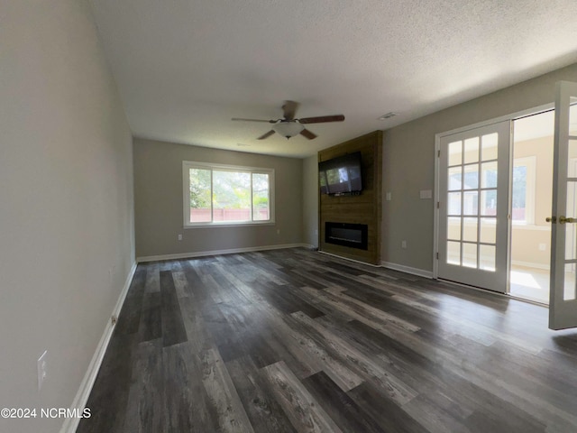 unfurnished living room with dark wood-type flooring, ceiling fan, a fireplace, and a textured ceiling