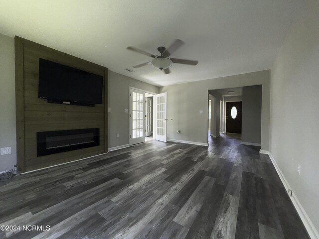 unfurnished living room with ceiling fan, a fireplace, and dark hardwood / wood-style flooring