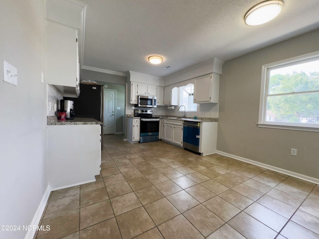 kitchen featuring stainless steel appliances, white cabinetry, plenty of natural light, and sink