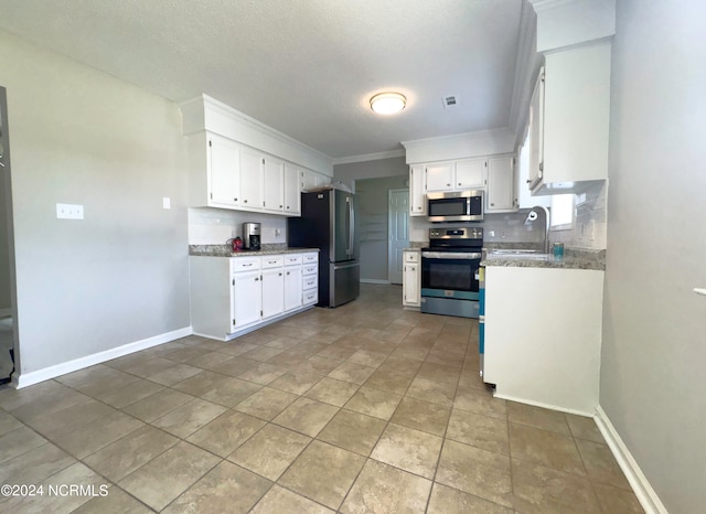 kitchen featuring ornamental molding, stainless steel appliances, white cabinets, and light stone countertops