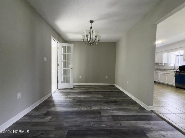 spare room with an inviting chandelier, dark wood-type flooring, and sink