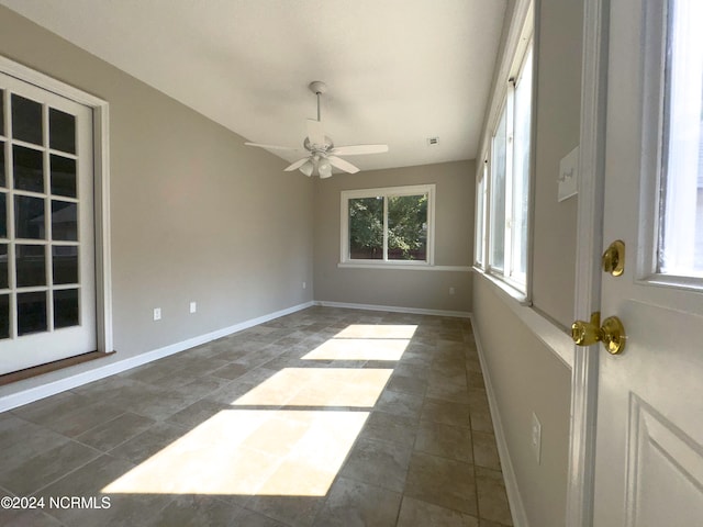 unfurnished room featuring ceiling fan and dark tile patterned flooring