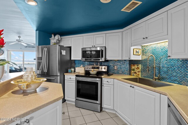 kitchen with appliances with stainless steel finishes, a kitchen island, backsplash, light hardwood / wood-style floors, and white cabinets