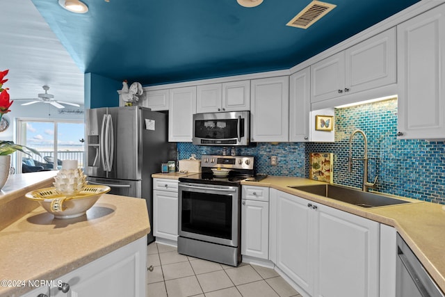 kitchen with visible vents, a sink, decorative backsplash, stainless steel appliances, and white cabinetry