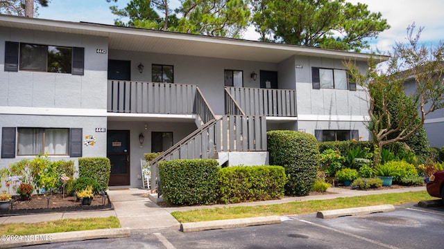 view of property featuring stairs and uncovered parking