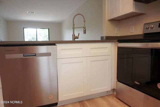 kitchen with appliances with stainless steel finishes, white cabinets, light wood-style flooring, and visible vents