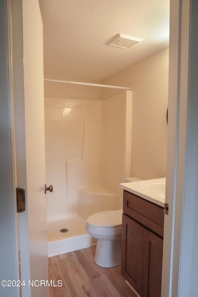 bathroom featuring a shower, toilet, vanity, and hardwood / wood-style flooring