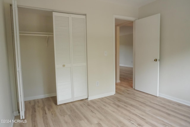 unfurnished bedroom featuring a closet, baseboards, and light wood finished floors