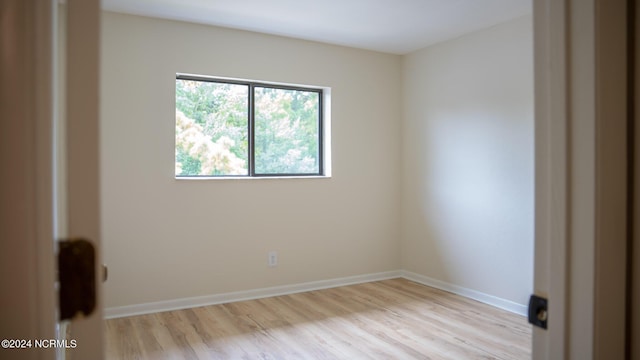 empty room featuring light wood finished floors and baseboards