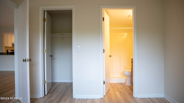 unfurnished bedroom with light hardwood / wood-style flooring, a closet, a spacious closet, and ensuite bathroom